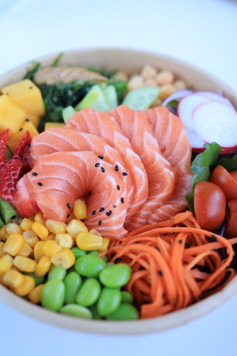 A colorful poke bowl with salmon, vegetables, and fruits, perfect for a healthy meal.